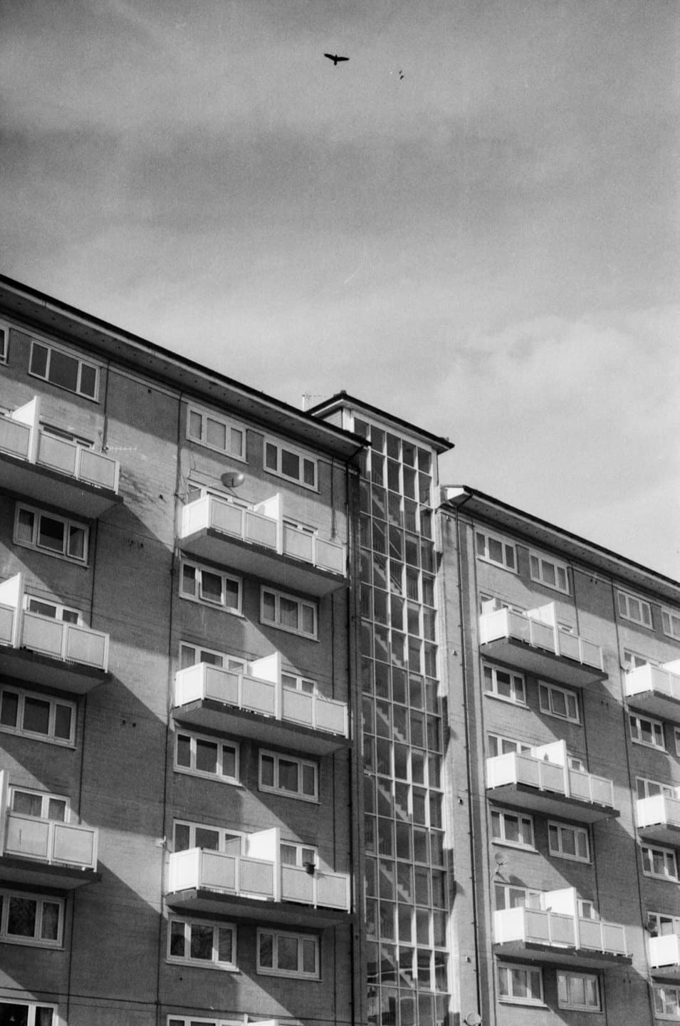 Beyaz balkonlu, çok katlı tuğla apartman binası.